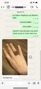 Gros plan d’une bague à pierre gravée rouge, tenue dans la main — bijou symbolique et raffiné inspiré de l’art islamique.