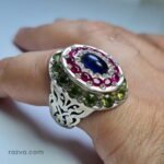 Bague artisanale ornée de rubis et péridots autour d’un saphir